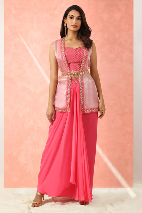 Bright pink drape skirt with matching crop top paired with baby pink jacket with embroidered belt.