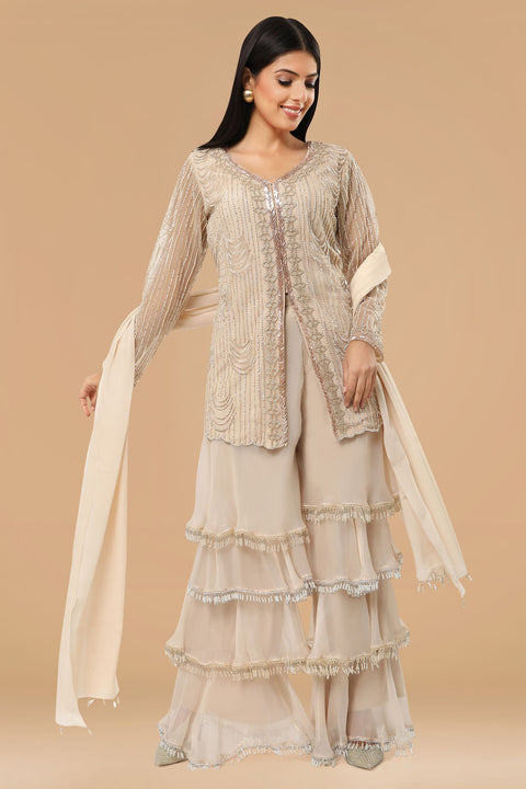 Beige jacket style embroidered tunic paired with multi layered gharara and crepe dupatta.